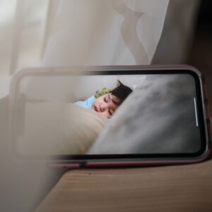Écran de smartphone affichant un bébé endormi via une caméra bébé — surveillance de la chambre