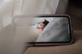 Écran de smartphone affichant un bébé endormi via une caméra bébé — surveillance de la chambre