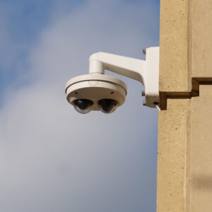 Deux caméras de surveillance extérieures montées sur un mur d'immeuble sous un ciel bleu