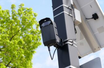 Caméra de surveillance extérieure avec panneau solaire sur mât, ciel bleu