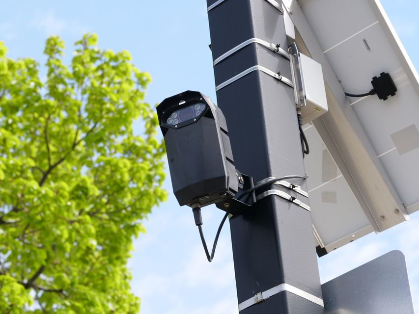 Caméra de surveillance extérieure avec panneau solaire sur mât, ciel bleu