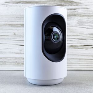 Caméra de surveillance blanche sur fond bois, type Foscam X5