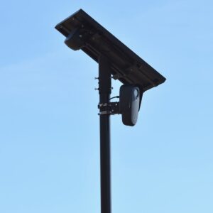 Caméra de surveillance extérieure alimentée par énergie solaire sur mât, ciel bleu