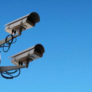 Deux caméras de sécurité montées sur un mât contre un ciel bleu dégagé