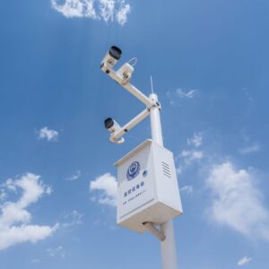 Deux caméras de sécurité blanches montées sur un mât sous ciel bleu nuageux