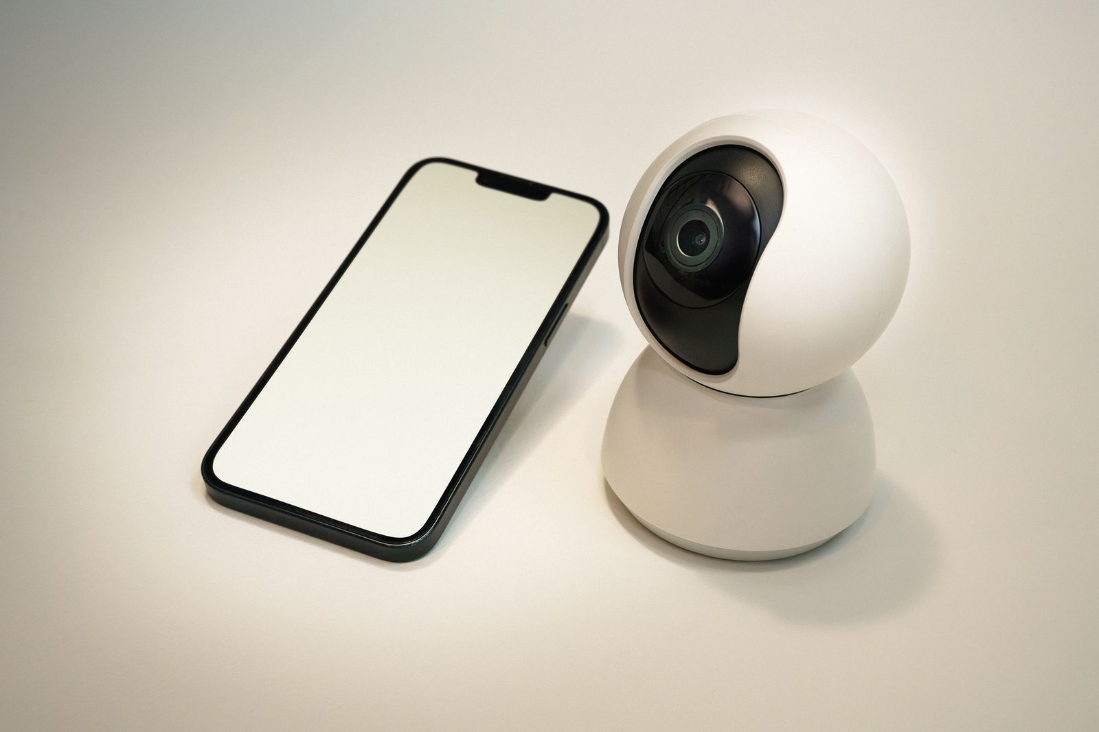 Caméra de sécurité intelligente Foscam X5 blanche posée à côté d'un smartphone, vue rapprochée